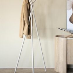 Moderne witte kapstok met artistieke design en een beige jas erop, passend in een strak en minimalistisch interieur.
