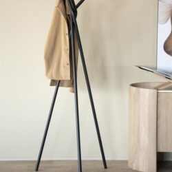 Beige jas aan een moderne zwarte garderobe standaard in een minimalistisch interieur.
