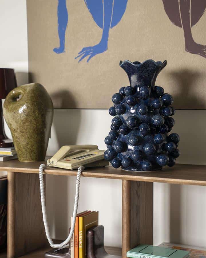 Kunstzinnige keramieke vazen op houten woonkamerbank, vintage telefoon en boekenkast, stijlvolle woondecoratie, Mokana Meubelen, unieke meubelstukken, design accessoires, modern interieurdesign, hoogwaardige keramiek, woondecoratie inspiratie.