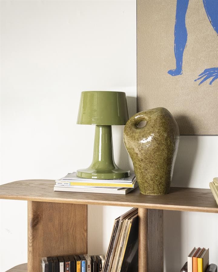 Klassieke groene tafel lamp en bijpassende vaas op houten boekenplank in een modern interieur.