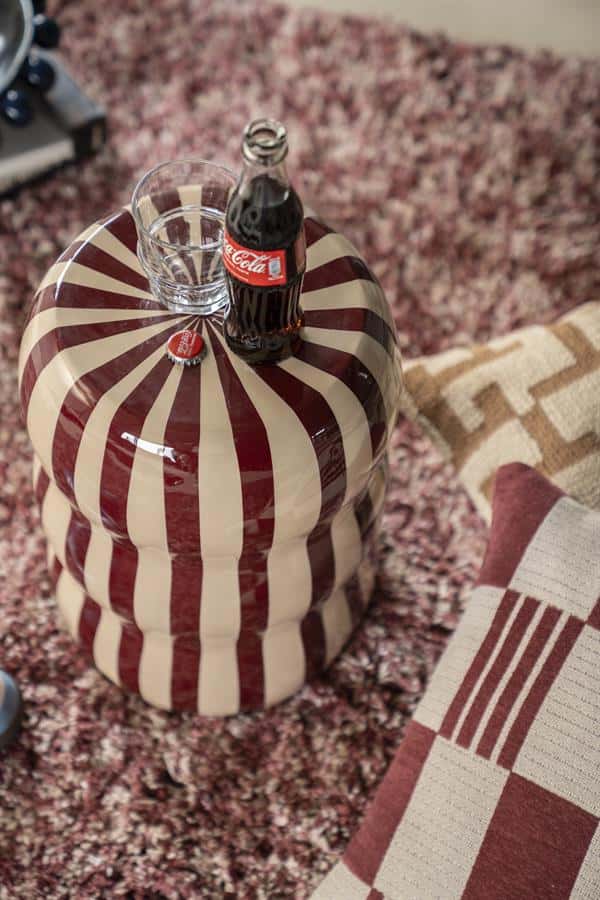 Kleine ronde salontafel met een uniek rood-wit gestreept patroon, ideaal voor Scandinavisch interieur.