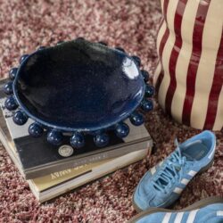 Uniek brocante stijl decor met vintage accessoires, blauwe sneakers, kamerscherm, en boeken, perfect voor een gezellige woonruimte.