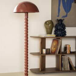 Unieke design vloerlamp met gedraaide standaard en ronde kap, gecombineerd met houten boekenkast en decoratieve vazen in een modern interieur. Perfect voor stijlvolle woonkamer of studeerkamer.