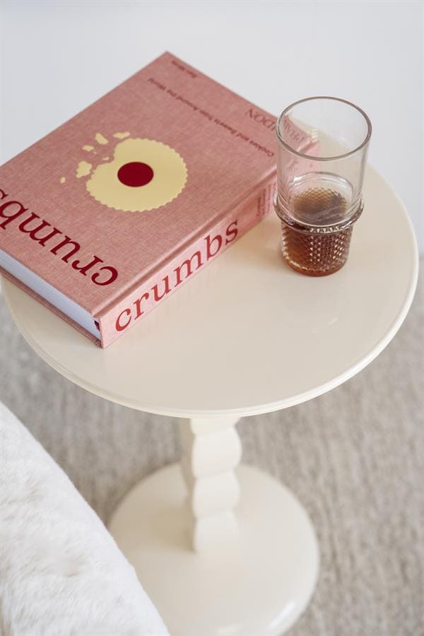 Crumb boek op een wit bijzettafeltje met een halfvolle glas cola, stijlvolle interieuraccessoires, Scandinavisch design, modern woonconcept, gezellig sfeer, Mokana Meubelen, kwalitatieve meubels, interieur inspiratie, design classics.