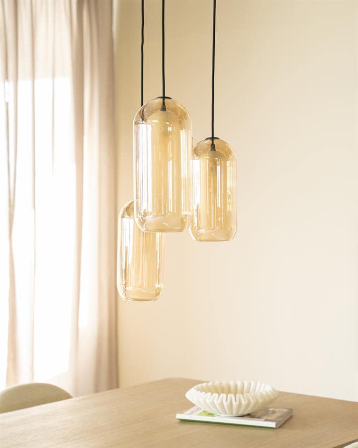 Strakke moderne hanglamp met vier amberkleurige glazen kappen boven eettafel. High-end design verlichting, perfect voor hedendaagse interieurs.