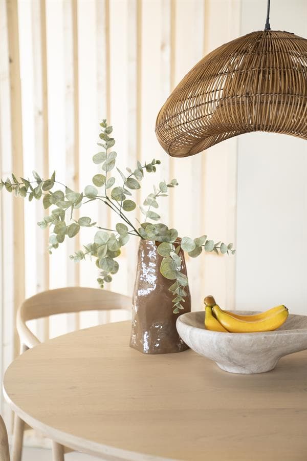Rustieke vaas met eucalyptus op een houten eettafel, moderne interieurdecoratie met natuurlijke materialen en pastelkleuren, sfeervol en stijlvol.