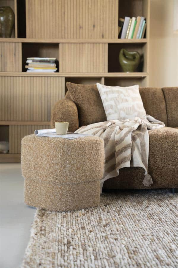 Klein, rond bijzettafeltje in zachte beige stof voor een warme woonkamerstijl.