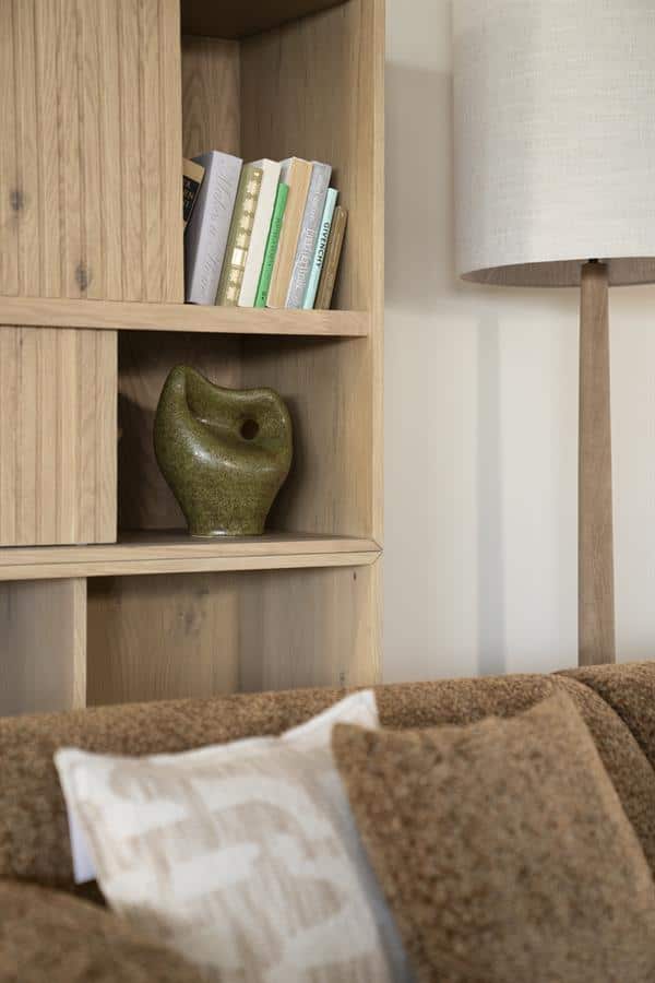 Grote houten boekenkast met decoratieve vazen en boeken, moderne woonkamer inrichting, natuurlijke materialen en warme sfeer,stijlvol meubelontwerp voor woonkamer of leeshoek.