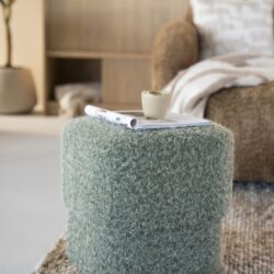 Knusse groene poef van vloerkleedstof in een moderne woonkamer met natuurlijke houten elementen en comfortabele zithoek. Perfect voor gezellige, Scandinavische interieurstijl.