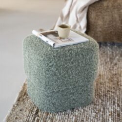 Tijdelijke blauwe stoffen kruk met een kopje en een opengeklapte tijdschrift op een beige tapijt, sfeer van een modern en cozy wooninterieur.