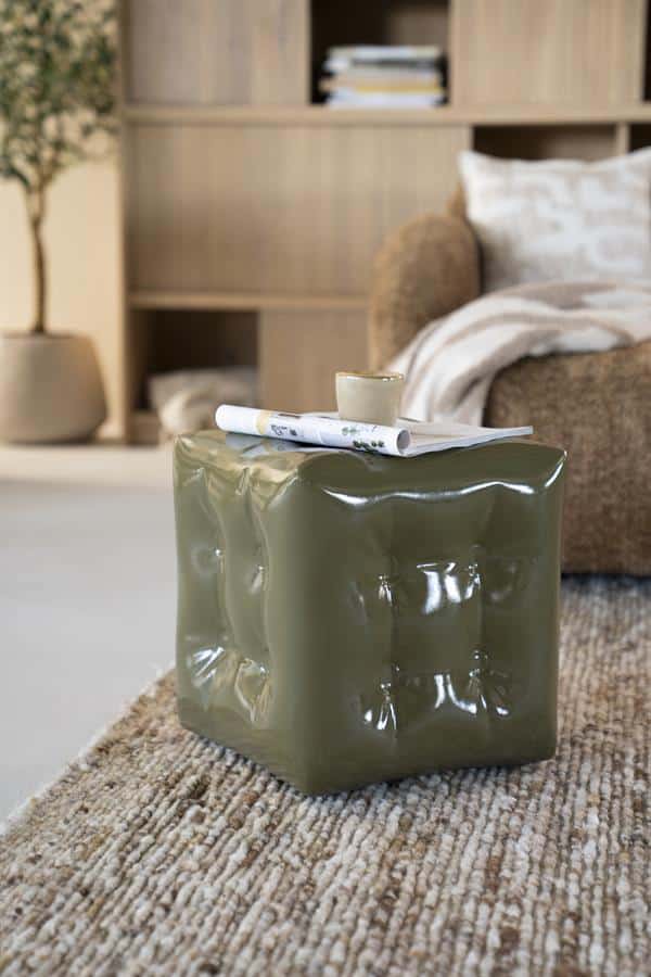 Kunststoffen bijzettafel in groen met een ruw oppervlak, op een beige tapijt in een stijlvolle woonkamer, modern woondecor, Mokana Meubelen.