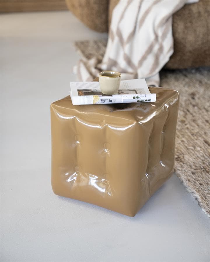 Zachte beige bijzettafel met plooien, modern design, in een woonkamer met zachte texturen en een leeslamp. Perfect voor een stijlvolle en functionele inrichting.