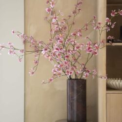 Bloemen in een marmeren vaas op een witte zuil, stijlvolle woondecoratie, kamerplanten, interieur design, Mokana Meubelen.