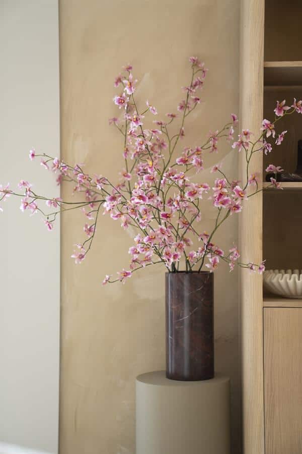 Bloemen in een marmeren vaas op een witte zuil, stijlvolle woondecoratie, kamerplanten, interieur design, Mokana Meubelen.