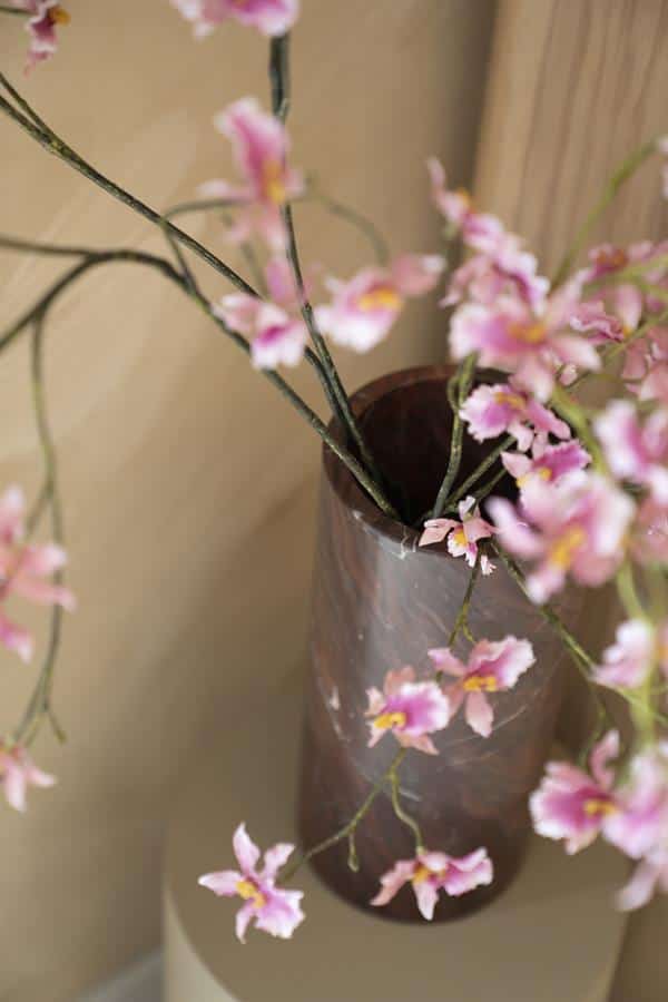 Zweefrozen bloemen in een glazen vaas op een bijzettafel, decoratief en stijlvol interieuraccessoire.