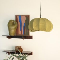 Unieke hanglamp met natuurlijke uitstraling, gecombineerd met decoratieve wandaccessoires en houten planken voor een stijlvolle interieurafwerking.