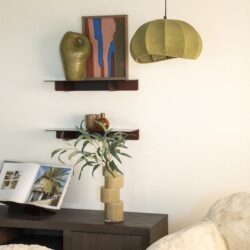 Nieuwe moderne woondecoratie met houten planken, keramische vazen, een boek en een groene lamp in een minimalistisch woonkamer interieur.