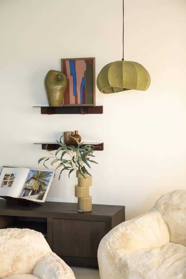 Nieuwe moderne woondecoratie met houten planken, keramische vazen, een boek en een groene lamp in een minimalistisch woonkamer interieur.