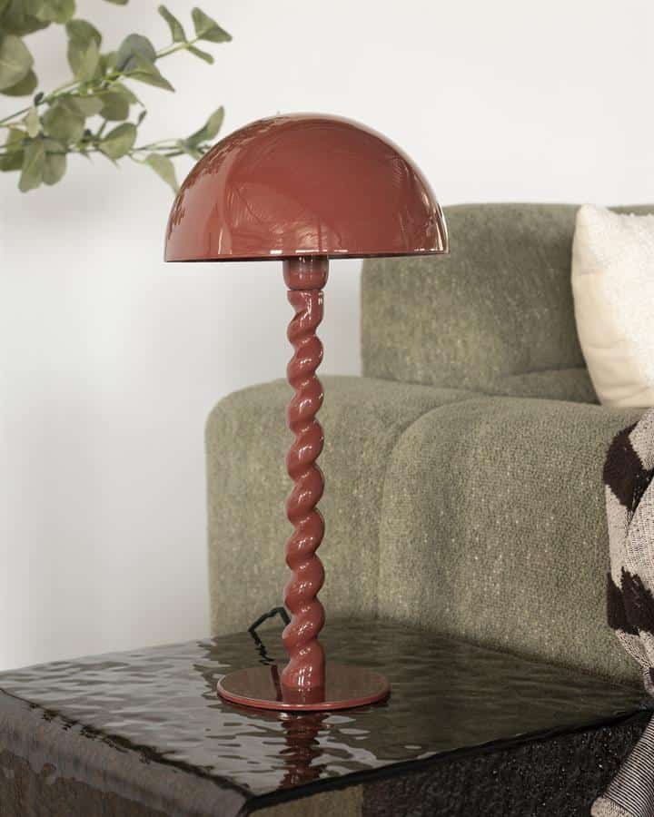 Dekoratieve vaaslamp met gedraaide staaf en halfbolvormige kap in terracotta kleur, perfect voor modern interieur.