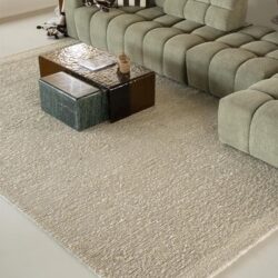 Moderne groene stoffen bank met bijzettafels in een sfeervolle woonkamer, gecombineerd met een lichtkleurig tapijt en stijlvolle decoratie, perfect voor een comfortabele zithoek.