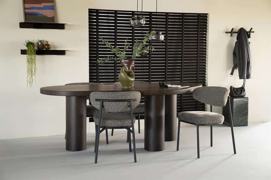 Stoel met vilt bekleding en metalen frame, donker houten eettafel met bloemstuk, modern interieur met wanddecoratie en planten, hoogwaardige meubels van Mokana Meubelen, perfect voor een stijlvolle eetruimte.