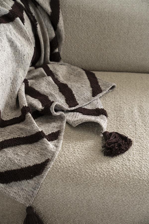 Zachte stoffen plaid met franjes op een comfortabele bank in een stijlvolle woonkamer.