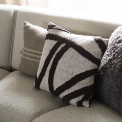 Zwarte en witte design patterned kussen op een beige bank, modern en stijlvol woontextiel.