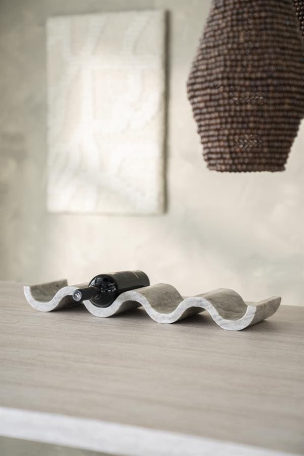 Elegante wijnfles in een uniek, golvend houten wijnrek op een modern houten tafel, met een kunstzinnig hanglamp en abstract muurkunst op de achtergrond, perfect voor stijlvol wonen.