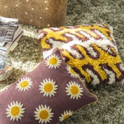 Gehaakte dekbedovertrek en sierkussens met bloemmotief op tapijt, perfect voor zacht en kleurrijk interieurdecoratie.