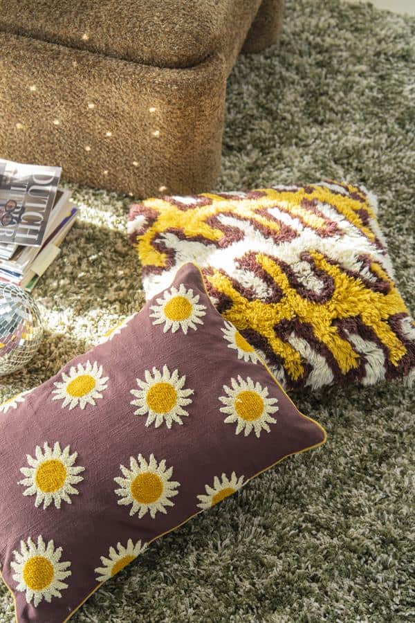 Gehaakte dekbedovertrek en sierkussens met bloemmotief op tapijt, perfect voor zacht en kleurrijk interieurdecoratie.