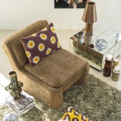 Kleine bank met grote bloemenkussen, bijpassende vloerkleed en moderne tafel met spiegeloppervlak, in een stijlvolle woonkamer.