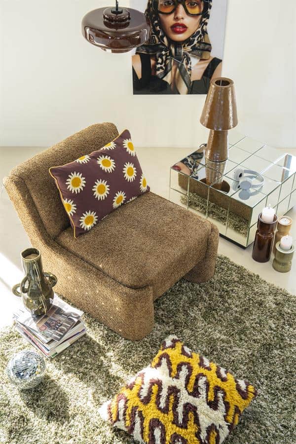 Kleine bank met grote bloemenkussen, bijpassende vloerkleed en moderne tafel met spiegeloppervlak, in een stijlvolle woonkamer.