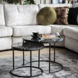 Grote zwarte marmeren bijzettafels met metalen onderstellen in een woonkamer setting met luxe bank en decoratieve kussens.