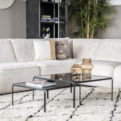 Elegante zwarte salontafels met glazen bladen, perfect voor moderne woonkamerinrichting en woonaccessoires, gecombineerd met een luxe loungebank en decoratieve vazen, op een stijlvolle witte en zwarte geometrische vloerkleed.