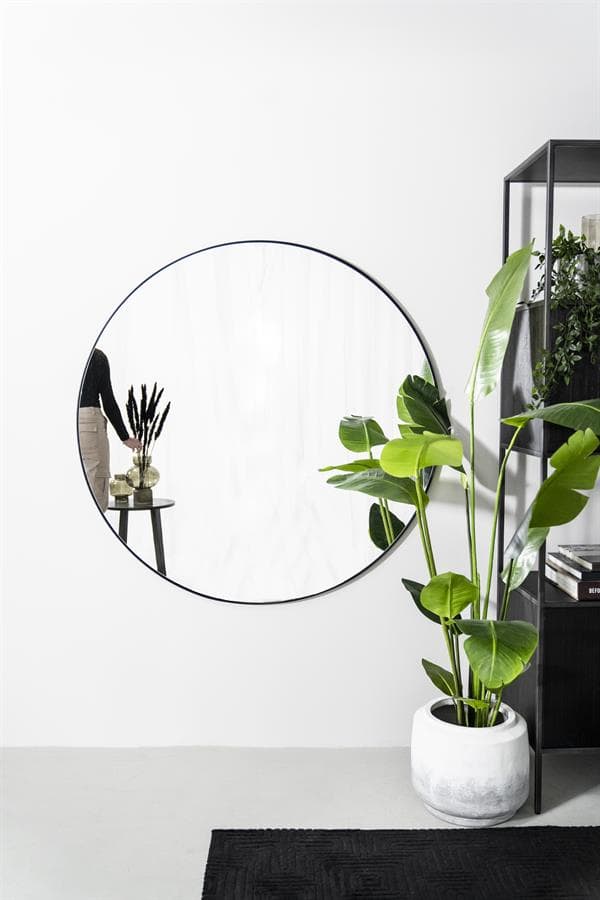 Grote ronde spiegel met zwarte rand en groene kamerplant in een witte pot, modern interieur decor, stijlvolle woonaccessoires voor een frisse uitstraling.