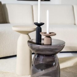 Zwart en helder glazen salontafels met decoratieve kandelaars in een modern woonkamer. Mokana Meubelen biedt stijlvolle en functionele meubelstukken voor een elegant interieur.