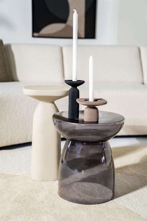 Zwart en helder glazen salontafels met decoratieve kandelaars in een modern woonkamer. Mokana Meubelen biedt stijlvolle en functionele meubelstukken voor een elegant interieur.
