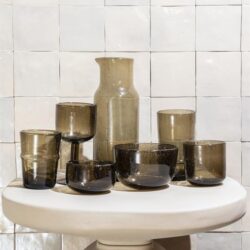 Kleine glazen vazen en kommen in aardetinten op een witte ovale tafel voor modern interieurdesign.