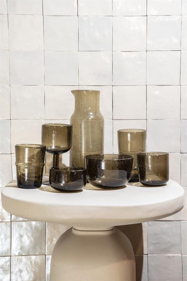 Kleine glazen vazen en kommen in aardetinten op een witte ovale tafel voor modern interieurdesign.