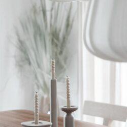Elegante witte kaarsenhouders met gedraaide kaarsen op een houten eettafel, perfect voor een sfeervolle en moderne interieurdecoratie.
