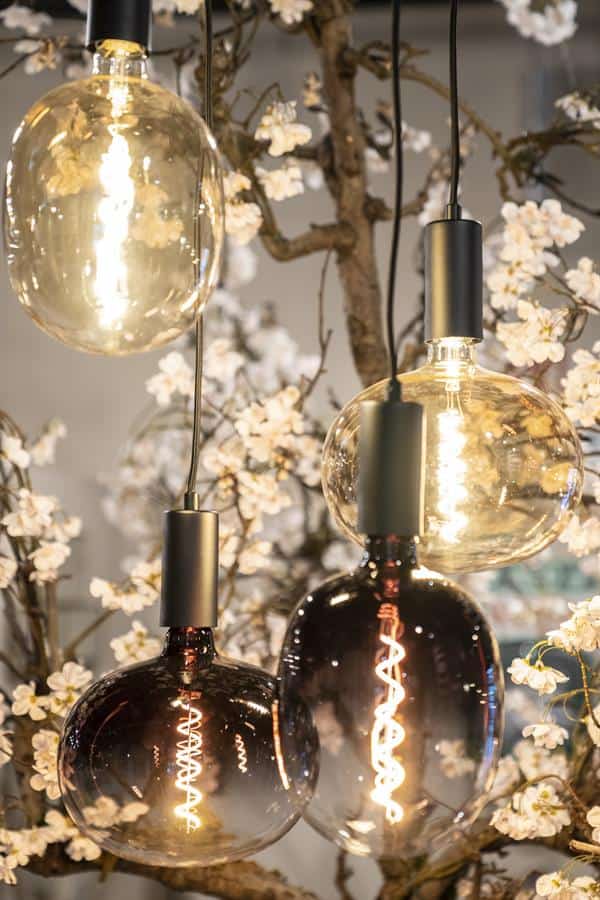 Geleidelijke close-up van moderne hanglampen met glazen bolvormen en warme filamentverlichting, perfect voor stijlvolle woonkamers en eetkamers met meubelen van Mokana.