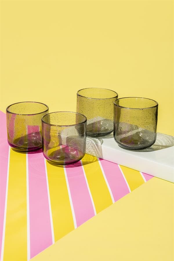 Kleurengetinte glazen bekers op een kleurrijk tafelblad met geel en roze strepen, perfect voor modern interieur en horeca.