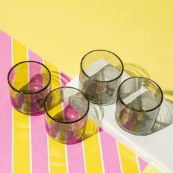 Glazen op een kleurrijke tafel met roze en gele strepen, perfect voor modern design en stijlvolle meubelaccessoires.