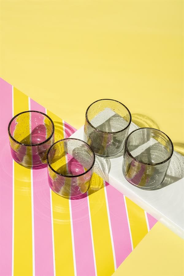 Glazen op een kleurrijke tafel met roze en gele strepen, perfect voor modern design en stijlvolle meubelaccessoires.