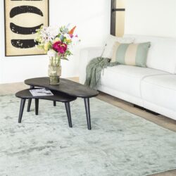 Vollgestoffeerde witte bank met sierkussens en plaid in een moderne woonkamer, gekleed met een lichtgrijze vloerkleed en zwart salontafel met bloemen en tijdschrift, stijlvolle inrichting door Mokana Meubelen, uniek meubelontwerp, comfort en design in één ruimte, perfect voor een gezellige zithoek.