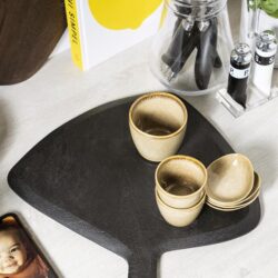 Kleurrijke theekopjes op een houten dienblad, stijlvolle keukenaccessoires voor een gezellige ontbijttafel.