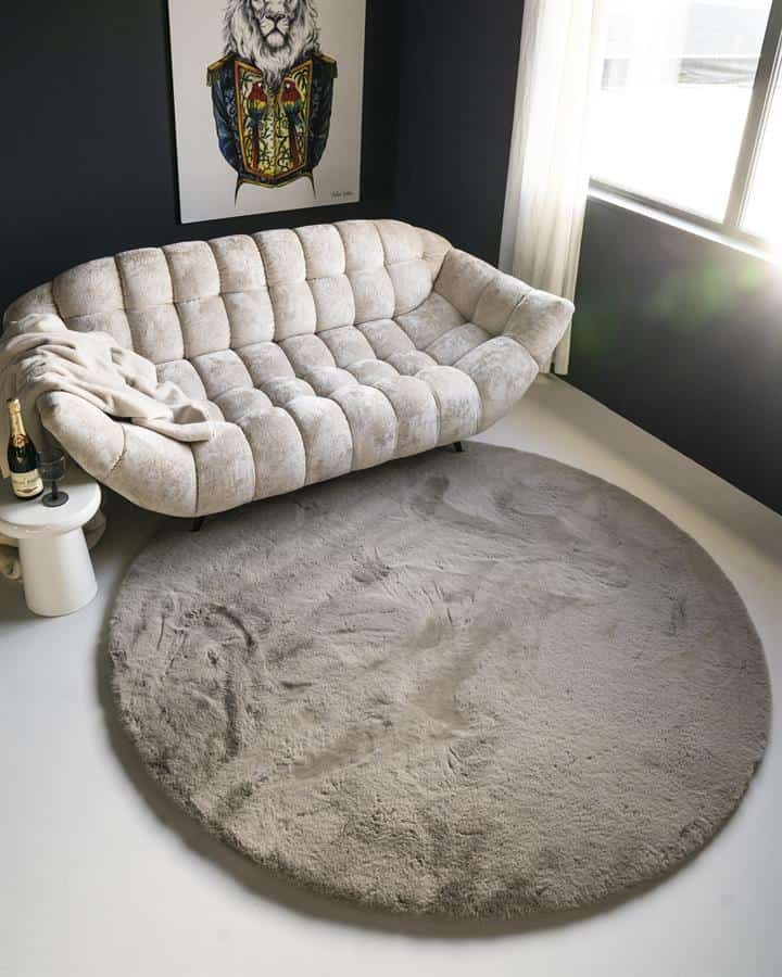 Luxe vintage velvet bank met elegante ronde beige vloerkleed en kunstzinnig lionportret op donkere muur voor stijlvolle woonkamer decoratie.