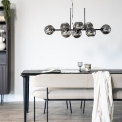 Minimalistisch luxe eetkamer met modern zwart houten eettafel en beige upholstered bank, verlicht door opvallende zwarte en zilveren hanglamp, perfect voor stijlvolle interieur inrichting.