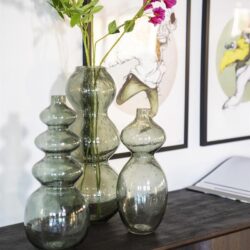 Glazen vazen met decoratieve bloemen op een houten console, geschikt voor modern en industrieel woonkamerinterieur.