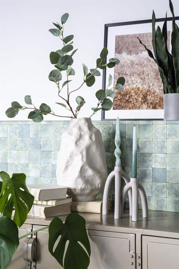 Gezicht op een moderne interieurdecoratie met groene planten, wandtegels en kaarsen, perfect voor stijlvolle woonkamers en natuurlijke sfeer.
